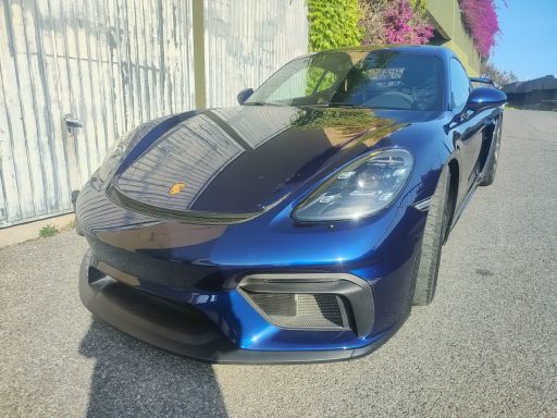 Voiture sportive bleue avec un design élégant, stationnée sur une route.